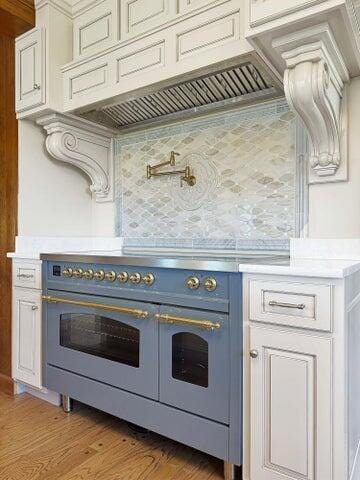 kitchen featuring decorative backsplash, double oven range, light countertops, premium range hood, and light wood-style floors