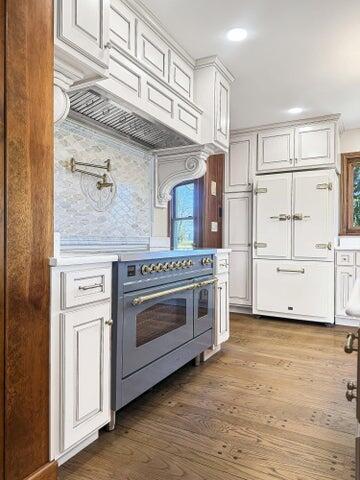 kitchen with a wealth of natural light, dark wood-style floors, double oven range, and tasteful backsplash