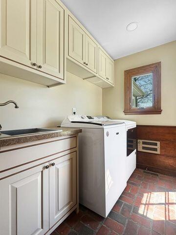 laundry area with cabinet space, a sink, brick floor, and washer and dryer