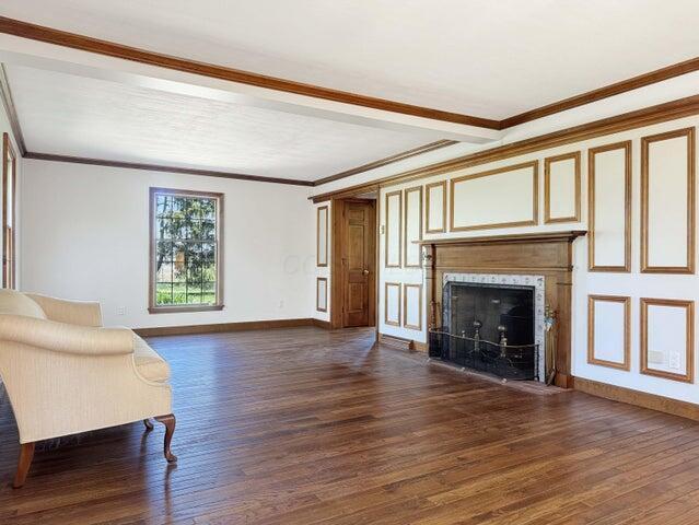 unfurnished living room featuring crown molding, a high end fireplace, baseboards, and dark wood-style flooring