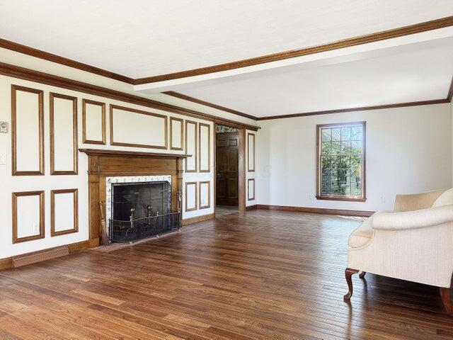 unfurnished living room featuring a high end fireplace, ornamental molding, baseboards, and wood finished floors