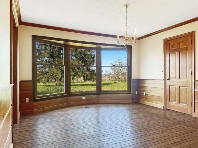 unfurnished dining area featuring a chandelier, wainscoting, a healthy amount of sunlight, and hardwood / wood-style flooring