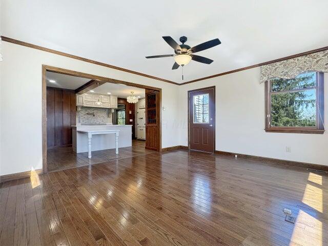 unfurnished living room featuring baseboards, ceiling fan with notable chandelier, and dark wood finished floors