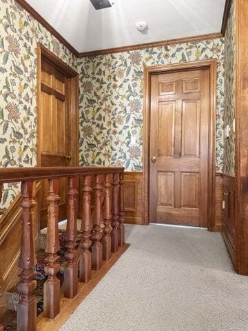 staircase featuring a wainscoted wall, ornamental molding, wallpapered walls, and carpet floors