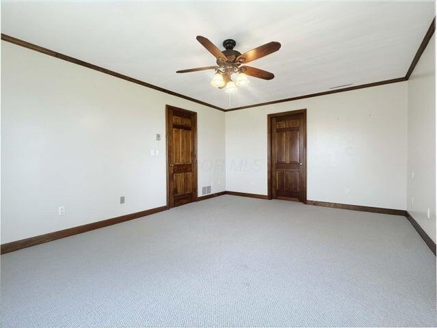 empty room featuring baseboards, ornamental molding, light carpet, and ceiling fan