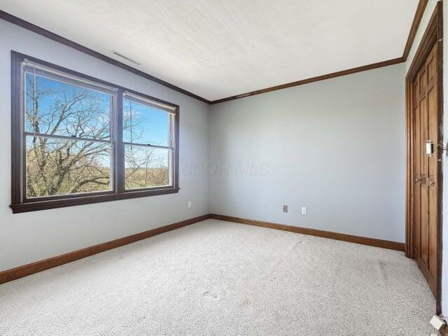 unfurnished room with crown molding, baseboards, and light carpet