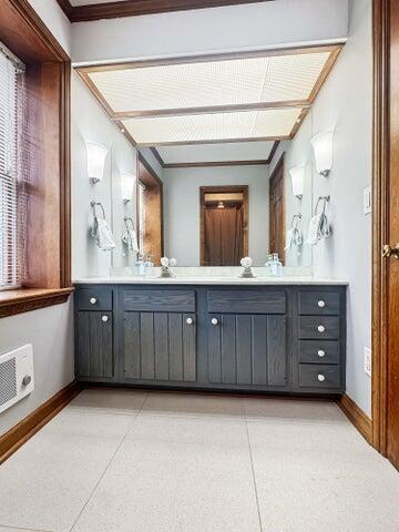 bathroom with tile patterned flooring, vanity, baseboards, a wealth of natural light, and ornamental molding