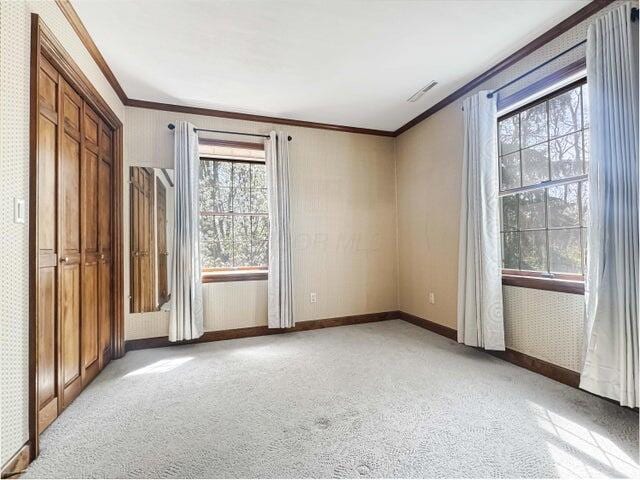 unfurnished bedroom with crown molding, baseboards, wallpapered walls, and light colored carpet
