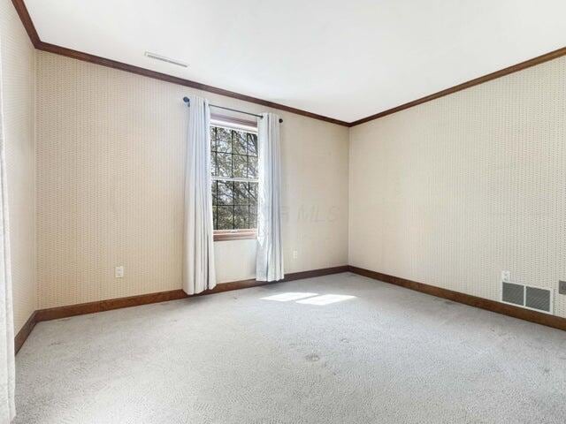 empty room with crown molding, baseboards, carpet, and visible vents