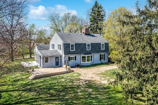 back of house with a chimney, a wooden deck, central AC, a gambrel roof, and a yard