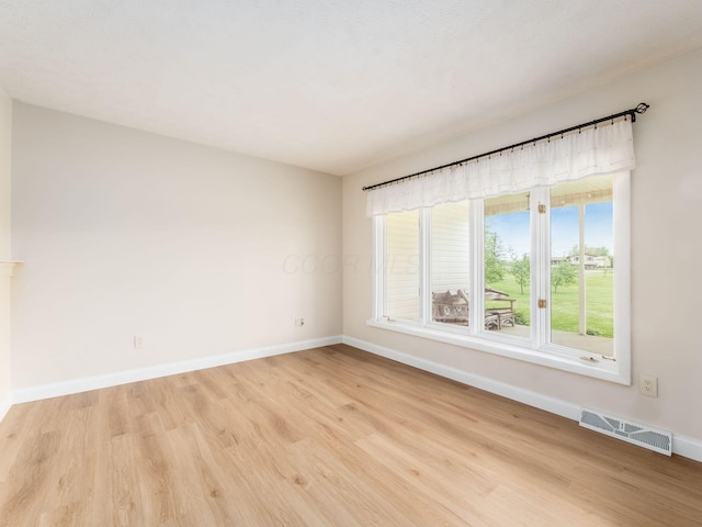 unfurnished room with visible vents, light wood-style flooring, and baseboards