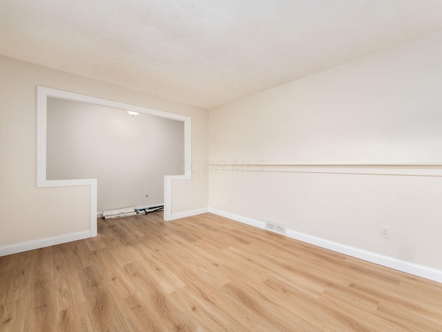 spare room with visible vents, baseboards, and light wood-type flooring