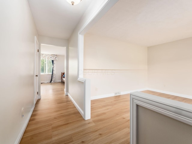 corridor featuring baseboards and light wood-style floors