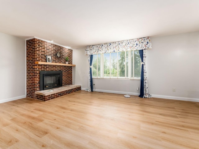 unfurnished living room featuring baseboards, a fireplace, and wood finished floors