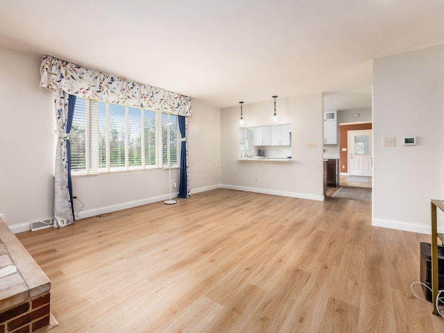 unfurnished living room with baseboards, plenty of natural light, and light wood-style floors