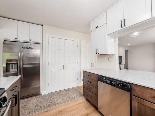 kitchen featuring light countertops, light wood finished floors, appliances with stainless steel finishes, and white cabinets