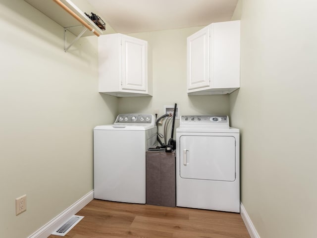 clothes washing area featuring cabinet space, separate washer and dryer, visible vents, and light wood finished floors