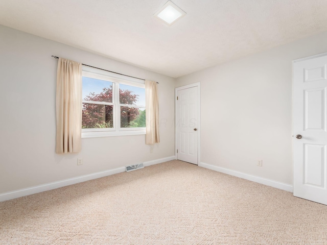 unfurnished room featuring baseboards, visible vents, and light carpet
