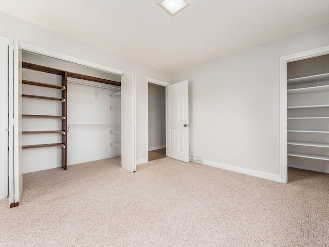 unfurnished bedroom featuring visible vents, baseboards, multiple closets, and carpet