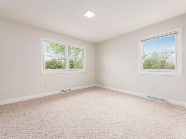 spare room featuring visible vents, carpet, and baseboards