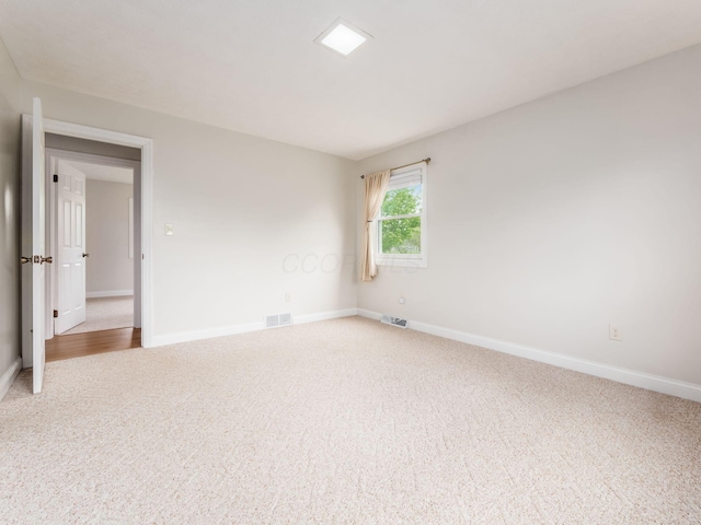 carpeted empty room featuring baseboards and visible vents