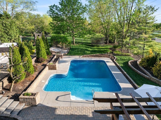 outdoor pool with a patio, a lawn, and fence