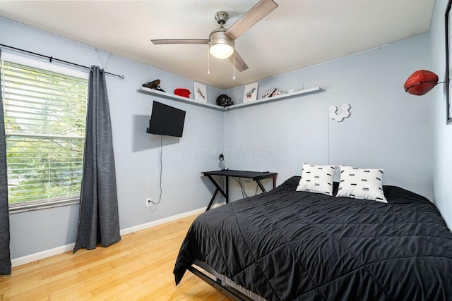 bedroom with ceiling fan, baseboards, multiple windows, and wood finished floors