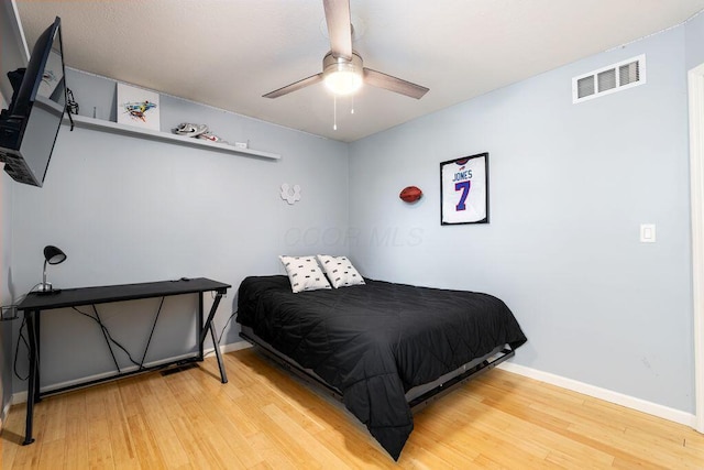 bedroom featuring ceiling fan, baseboards, visible vents, and wood finished floors