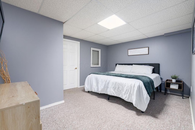 carpeted bedroom with baseboards and a drop ceiling