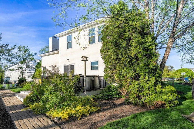 exterior space featuring fence, a chimney, and stucco siding