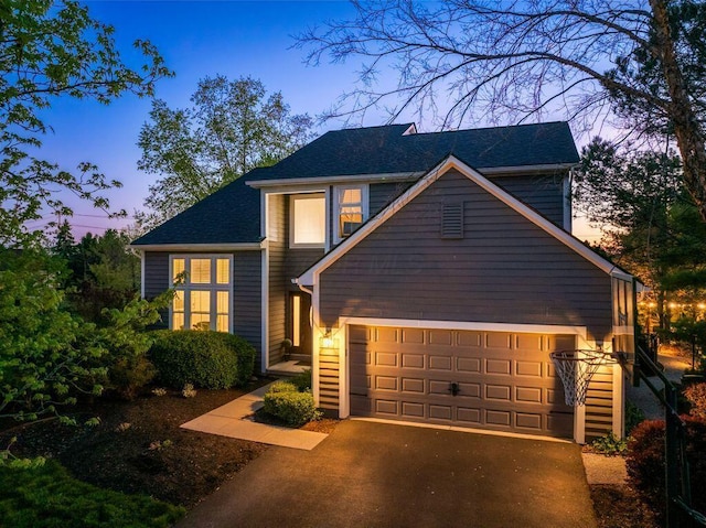 view of front facade with a shingled roof, an attached garage, and driveway