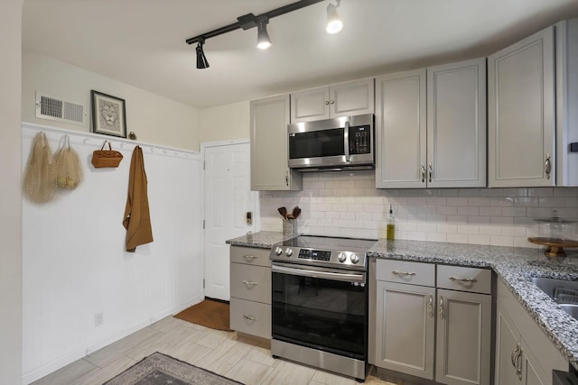 603 S James Rd, Columbus, OH 43213 - kitchen featuring stainless steel appliances, light stone countertops, gray cabinetry, and decorative backsplash