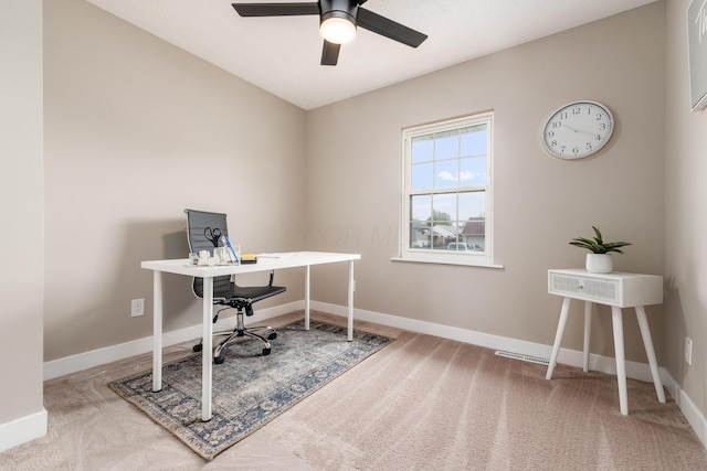 carpeted office space featuring a ceiling fan and baseboards