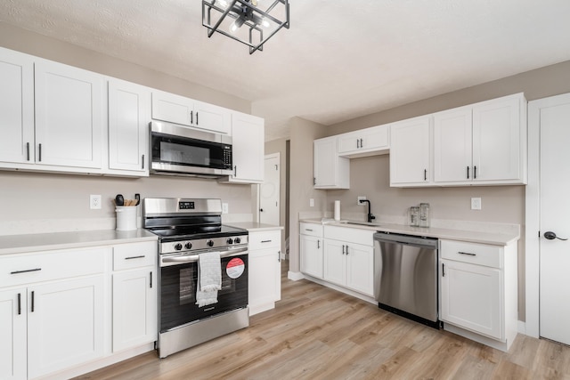 kitchen with stainless steel appliances, light wood-type flooring, and light countertops