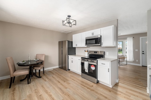kitchen featuring appliances with stainless steel finishes, light countertops, light wood-style flooring, and baseboards