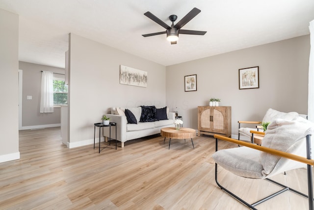 living room featuring light wood finished floors, ceiling fan, and baseboards