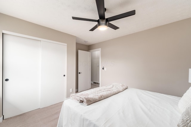 bedroom featuring light colored carpet, a closet, and ceiling fan