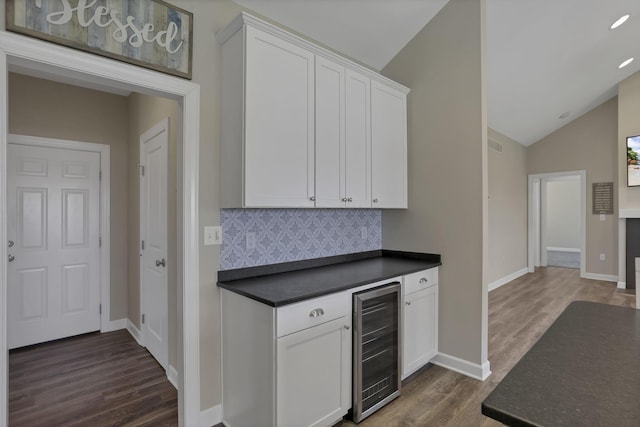 bar featuring decorative backsplash, dark wood-style floors, beverage cooler, and lofted ceiling