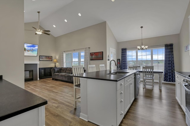 kitchen featuring a sink, high vaulted ceiling, a healthy amount of sunlight, and dark countertops