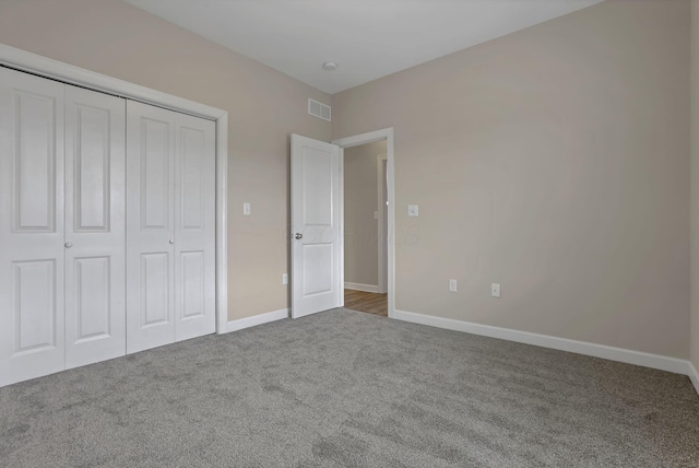 unfurnished bedroom featuring visible vents, carpet flooring, baseboards, and a closet