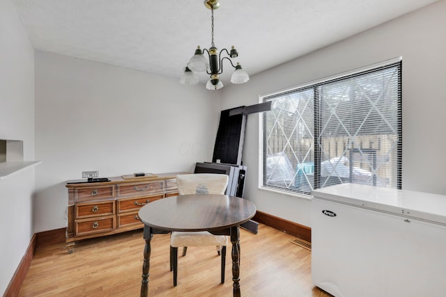 office space with baseboards, a notable chandelier, and light wood finished floors