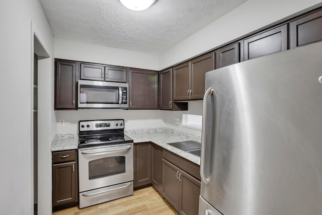 kitchen featuring light wood-type flooring, light countertops, dark brown cabinetry, and stainless steel appliances