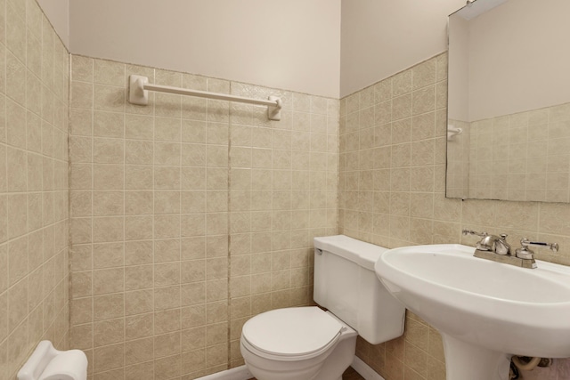 half bath with a sink, tile walls, and toilet