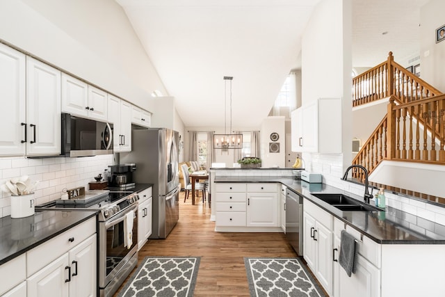kitchen with a peninsula, a notable chandelier, dark countertops, and stainless steel appliances