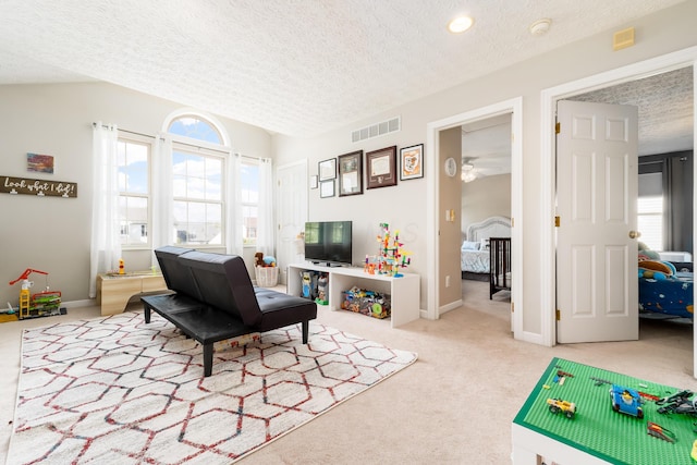 carpeted living room with a ceiling fan, a textured ceiling, and visible vents