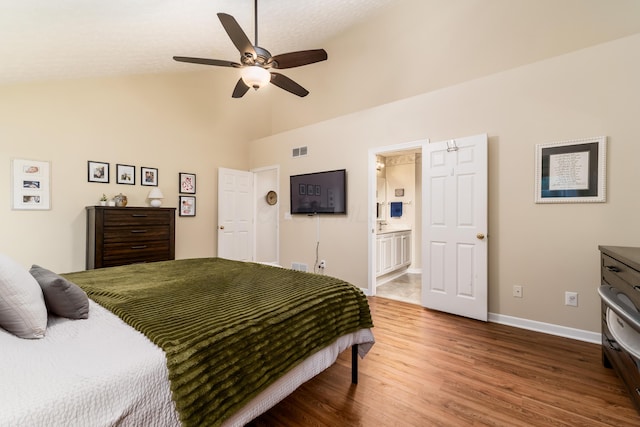bedroom featuring high vaulted ceiling, baseboards, wood finished floors, ensuite bathroom, and visible vents