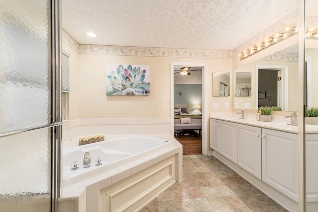 full bath featuring a sink, a textured ceiling, a ceiling fan, and a garden tub