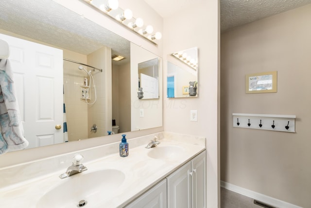 bathroom featuring double vanity, toilet, a textured ceiling, and a sink