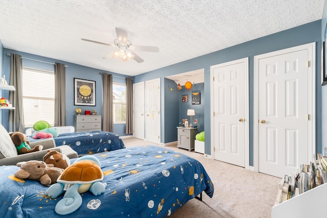 bedroom with multiple closets, ceiling fan, a textured ceiling, and carpet floors