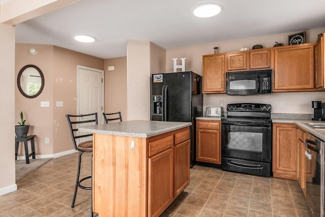kitchen featuring a center island, light countertops, black appliances, and a kitchen bar